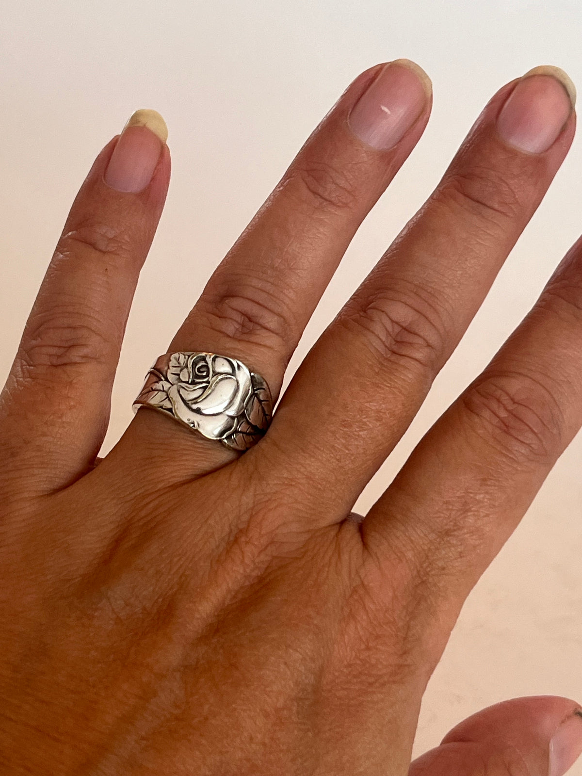 Ring af gammelt bestik båret på hånden, dramatisk rosenring med botanisk motiv og naturlig patina, lavet af Monnas Smykkedesign
