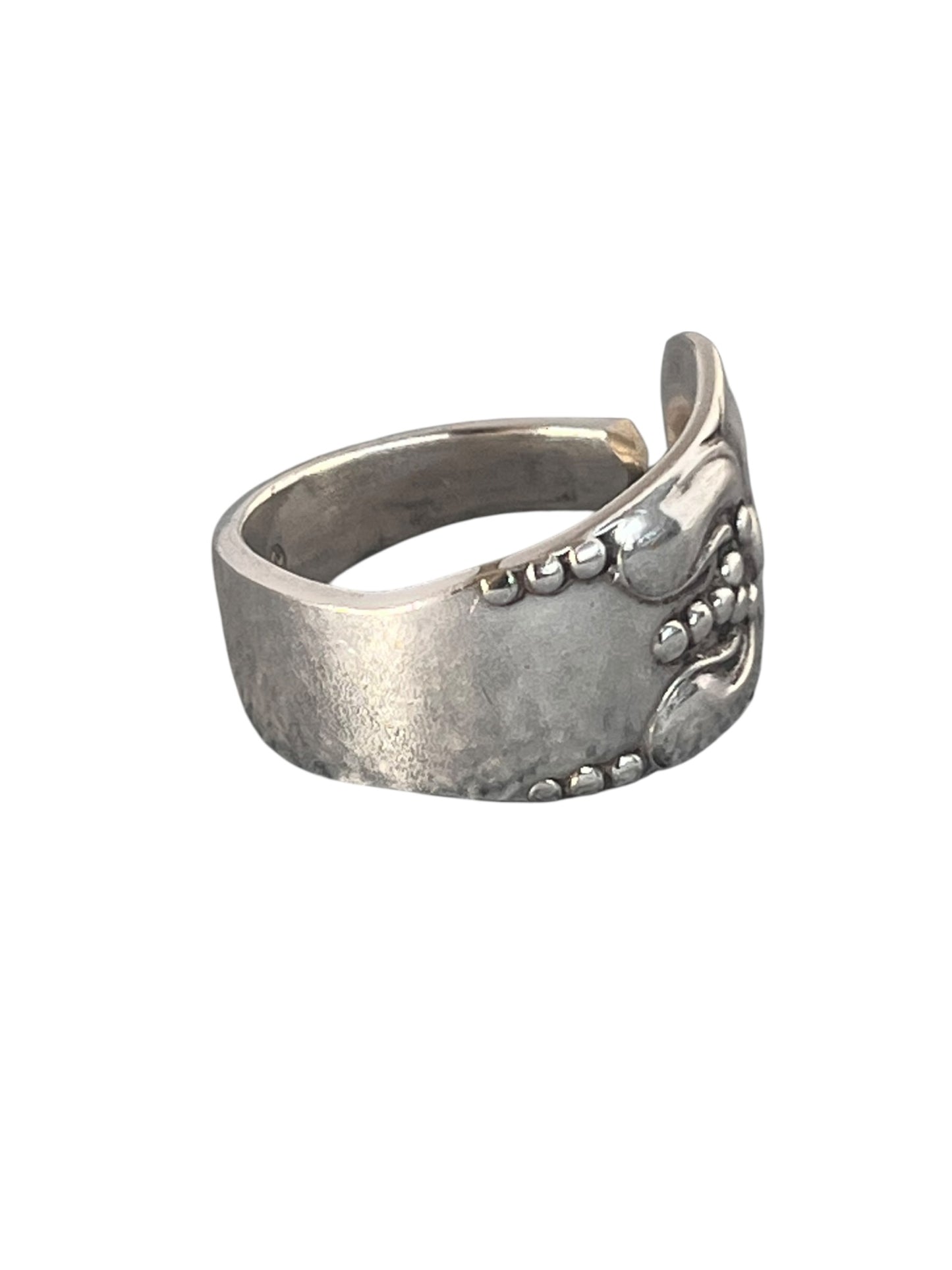 Nærbillede af ring af gammelt bestik med blomstermotiv og rolig overflade i sølvplet, lavet af Monnas Smykkedesign