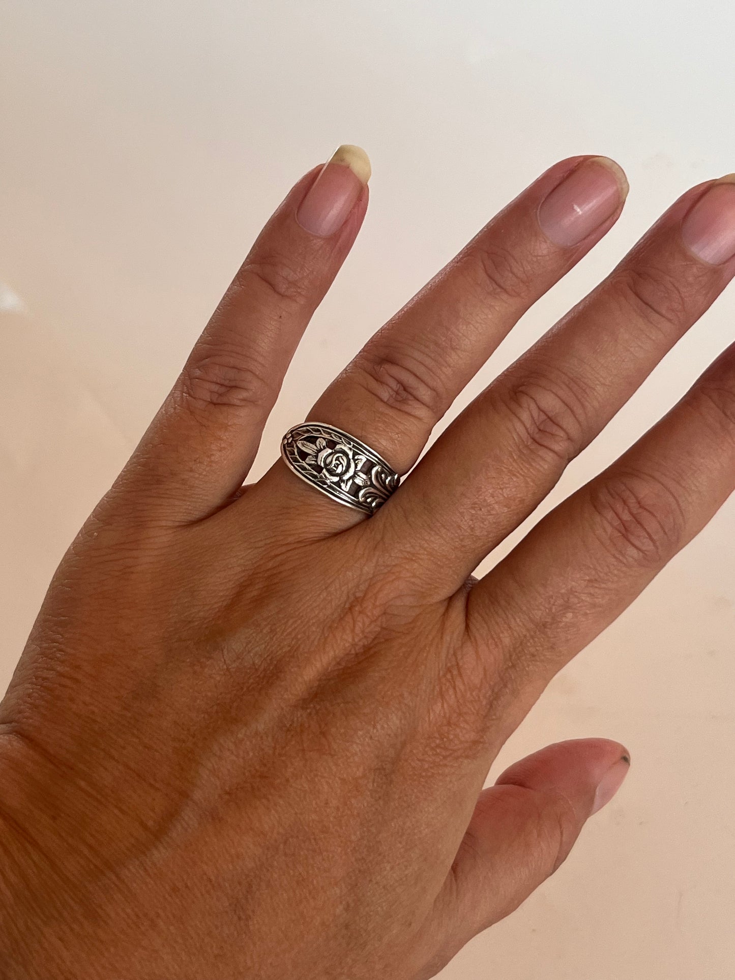 Ring af gammelt bestik båret på hånden, håndlavet genbrugssmykke af antik svensk teske med blomster og hulmønster i skønvirke-stil. Monnas Smykkedesign 